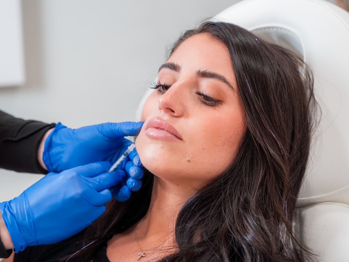 An injector places filler at a patient's chin