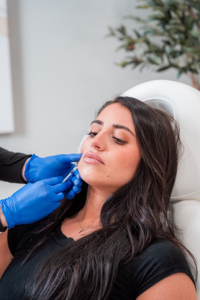 An injector places filler at a patient's chin
