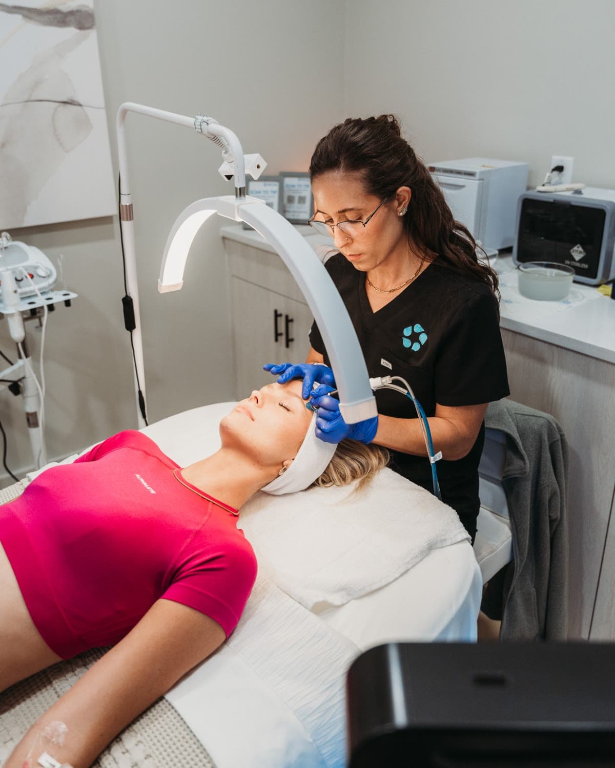 An aesthetician performs a HydraFacial under a ring light