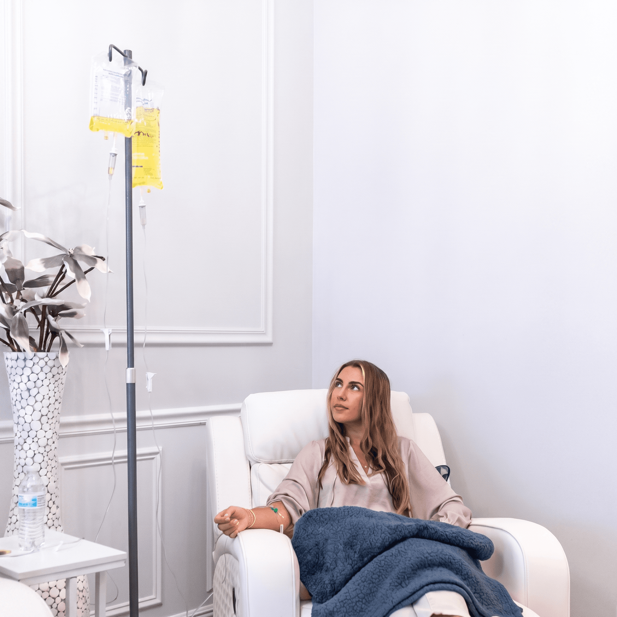 A patient relaxes under a blanket in a white recliner during a vitamin IV infusion at Relive Health Stuart